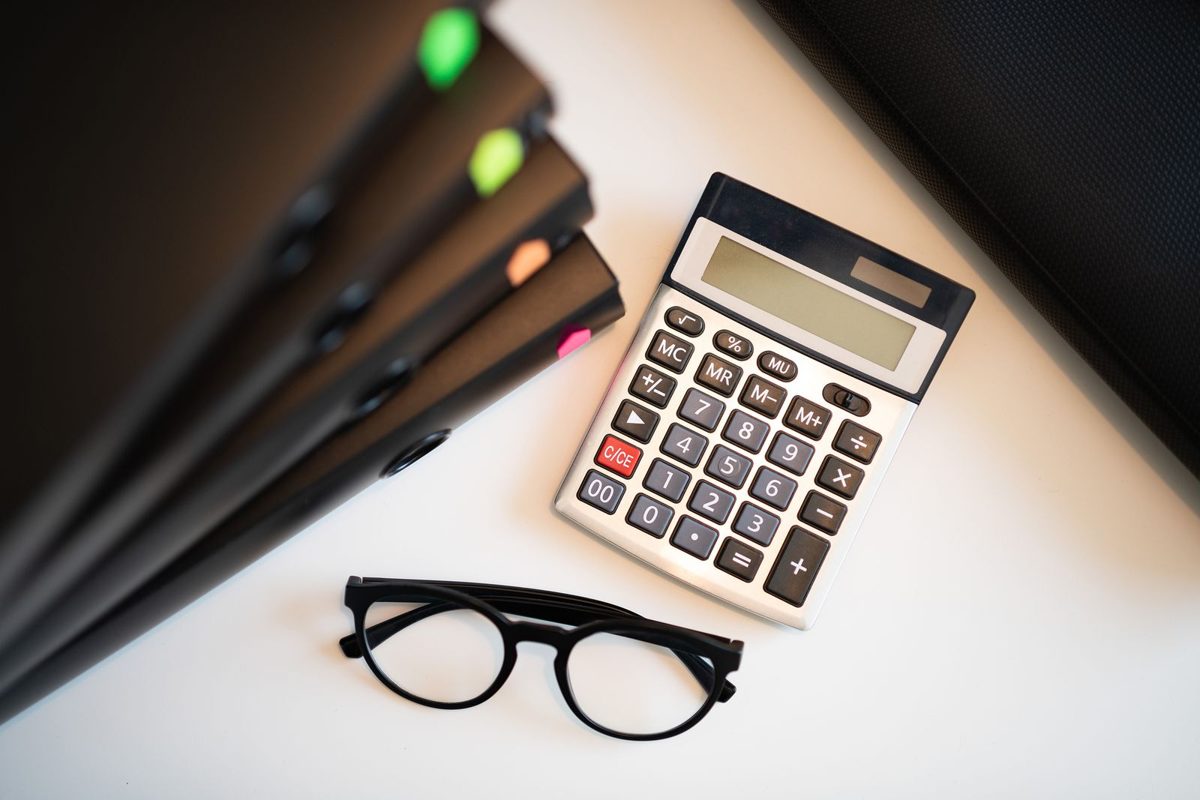 Calculadora, carpetas y gafas sobre un escritorio
